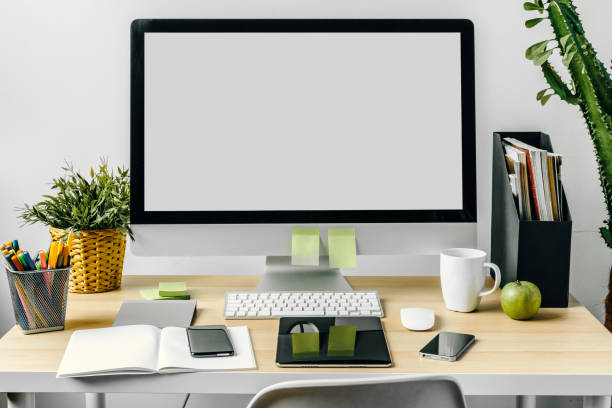 istock Computer monitor with mockup white screen on office table with supplies 1345457115