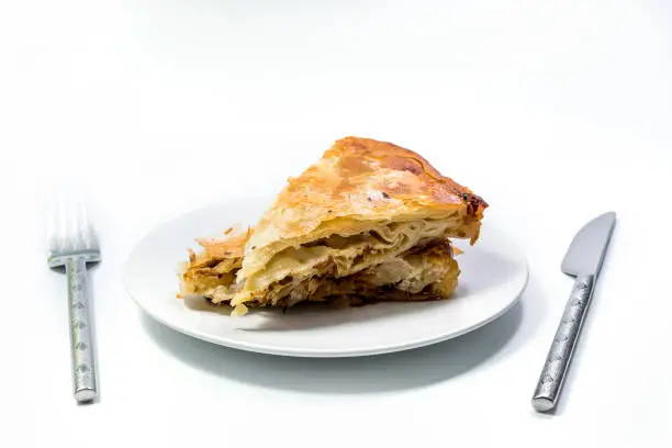Burek Traditional Pie With Meat Served On The Plate with ustenils. Traditional Balkan breakfast. Isolated on white background. Top View