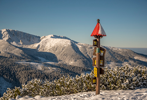 Tatra Mountains, Slovakia - December 1st 2020: wooden signpost with the name of Lucna Peak, it's height and hiking directions. Information sign for tourists.