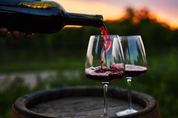 Pouring red wine into glasses on the barrel Pouring red wine into glasses on the barrel at dusk vineyard stock pictures, royalty-free photos & images