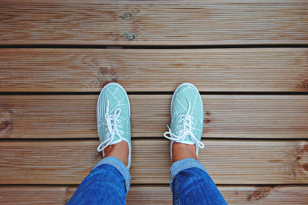 istock Women's legs in mint green sneakers on terrace board with copy space 1345464336