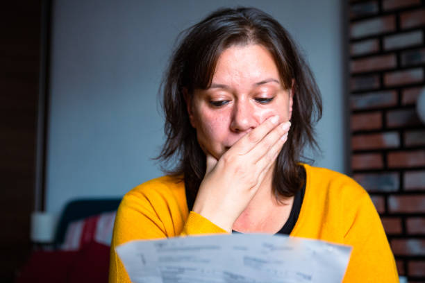 mujer preocupada revisando facturas en casa - debt fotografías e imágenes de stock