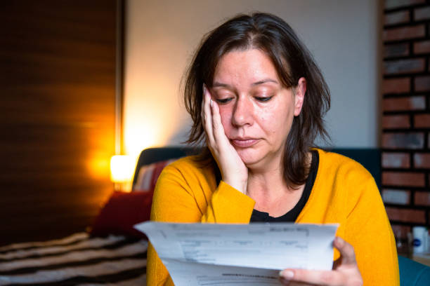 mujer preocupada revisando facturas en casa - energy bill fotografías e imágenes de stock