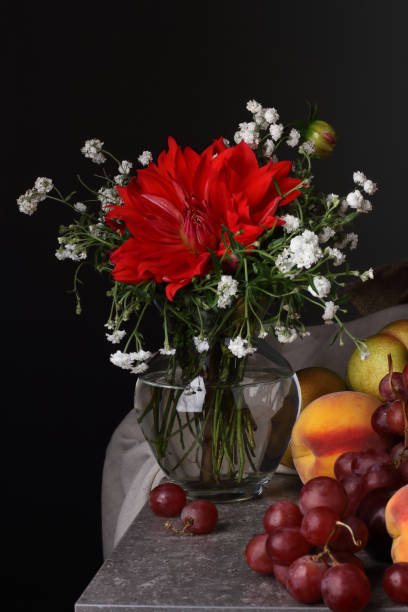 istock Still life with a red flower and fruit on a dark background 1345467868