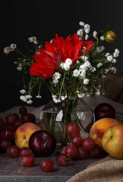 istock Still life with a red flower and fruit on a dark background 1345467869