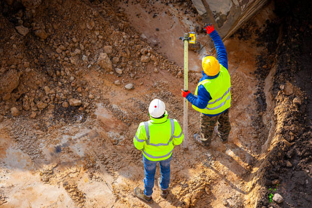 Construction crew using a laser level to ensure precise trench depth