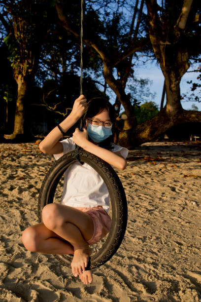 ragazza adolescente sull'altalena di pneumatici, che indossa la maschera facciale - freedom tire swing tire swing foto e immagini stock