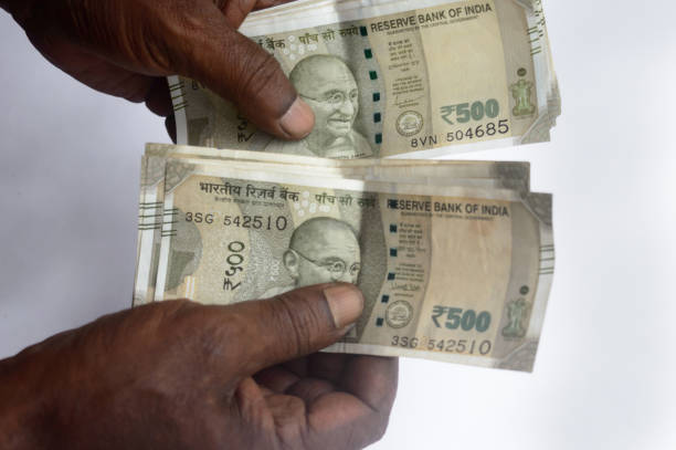 istock Senior aged Man hand counting Indian rupee note on table. High angle view. Close up. 1345472303