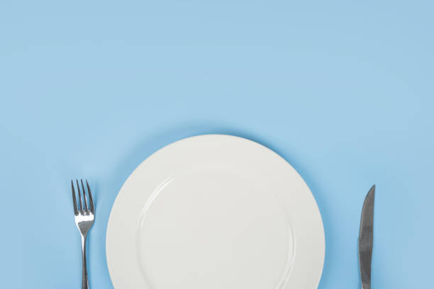 istock Plate with fork and knife on blue background isolated. 1345472450