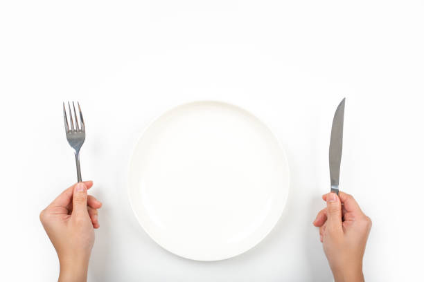 istock Woman with fork, knife and empty plate on on a on a white background, top view. 1345472499