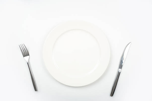 istock White plate with fork and knife for cutting meat pieces on white background isolated, with copy space. 1345472505