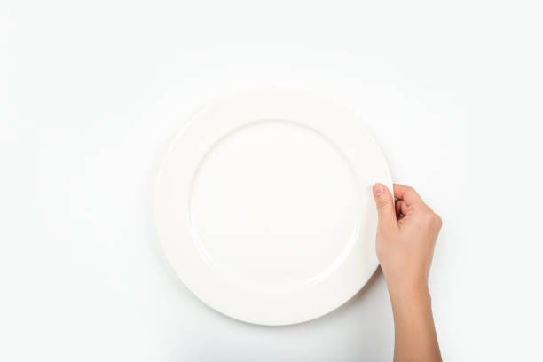 istock Woman with empty white circle plate on white background, top view. She is hungry. 1345472519