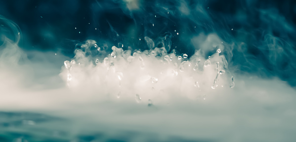 Abstract BANNER. Real Mystic smoke cloud with water drops blast, steam flying motion, dark background. Chemical experiment, aromatherapy, burn drink vapor, paranormal fog. Blue tone More colour stock