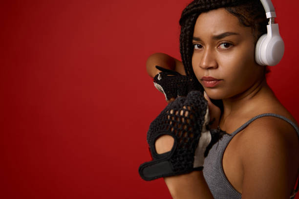 сконцентрированная молодая африканская спортивная женщина-боксер в наушниках и красных боксерских перчатках, глядя на камеру, делающую пр - muay thai audio стоковые фото и изображения