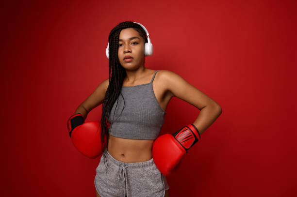 контактная концепция боевого искусства. молодая спортивная женщина-боксер в беспроводных наушниках и спортивной одежде, кладет руки с бок� - muay thai audio стоковые фото и изображения