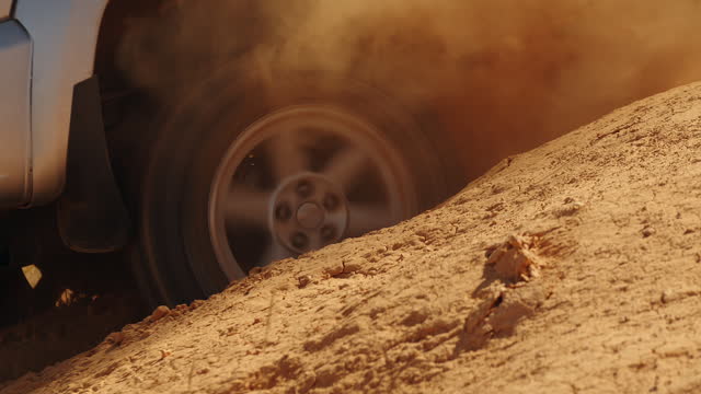 Closeup of an SUV wheel skidding in hole on off road, side view. Car is stuck in sand pit and is trying to leave