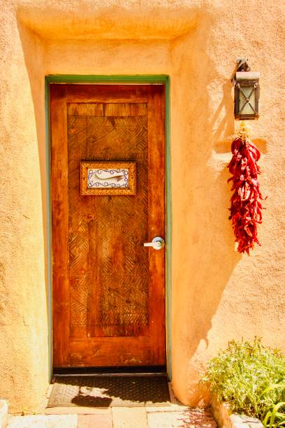 Vertical closeup photo of the wooden front door of a traditional adobe house front in Santa Fe, New Mexico in Summer.