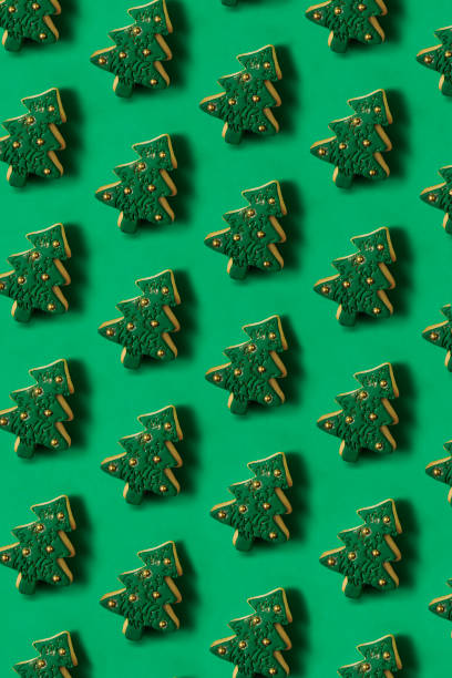 Christmas tree shaped cookies in a row on green background
