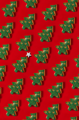 Christmas tree shaped cookies repetition in a row on red background