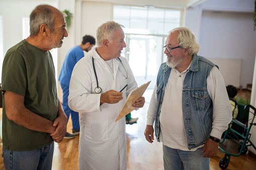 Doctor having a conversation with senior men in nursing home