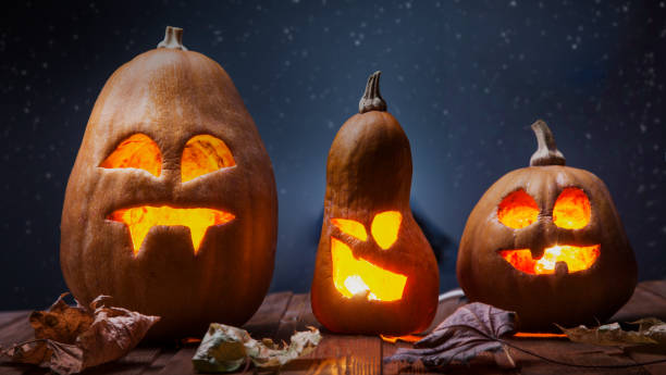 istock Jack o lanterns Halloween pumpkin face on wooden background 1345482517