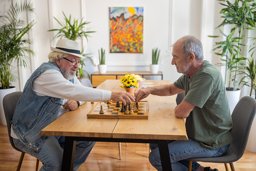 Two senior men enjoying chess game at nursing home