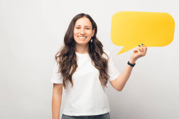istock Cheerful girl smiling at the camera is holding a yellow speech bubble. 1345483684