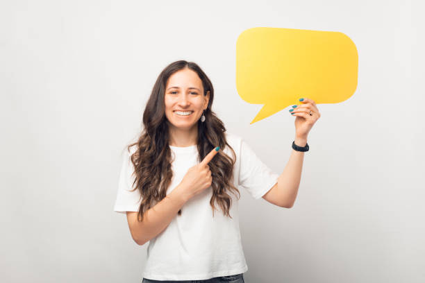 istock Cheerful girl is holding a yellow speech bubble and pointing at it. 1345483688