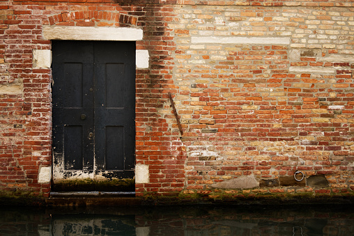 Brick wall of a house with doorway from the canals in Venice, Italy