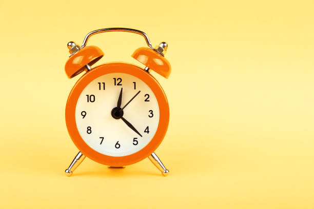 istock Close up one orange alarm clock over yellow background 1345484164