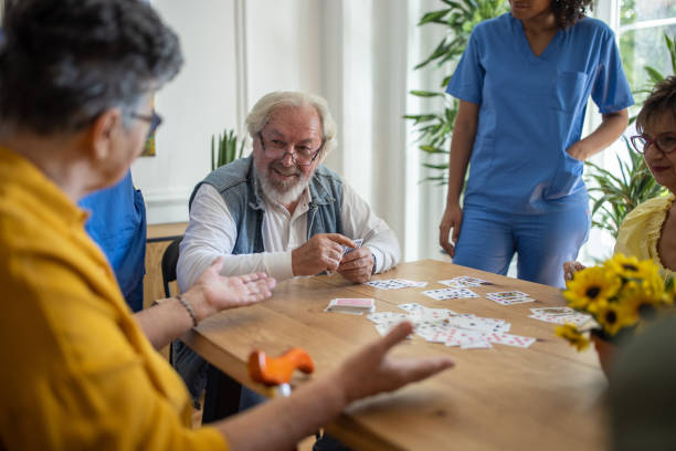 istock Happy senior people playing card at nursing home 1345484180