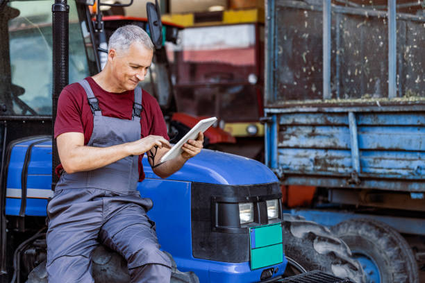 istock Farmer with digital tablet in front of farming equipment 1345485192