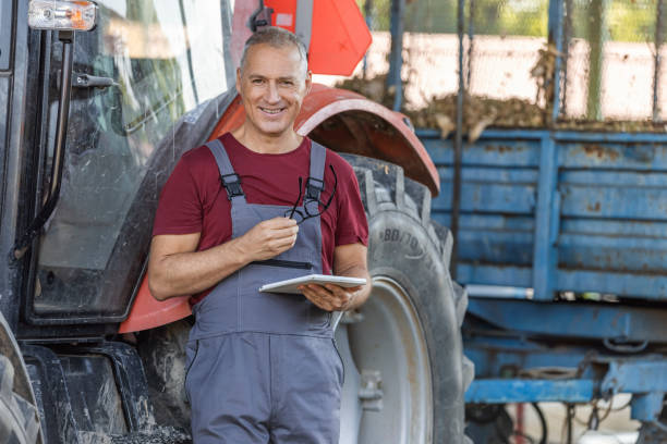 mature male farmer using a digital tablet, looking at camera with smile. - photography gray hair farmer professional occupation imagens e fotografias de stock