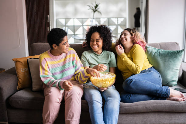istock Friends watching TV and eating popcorn at home 1345487681