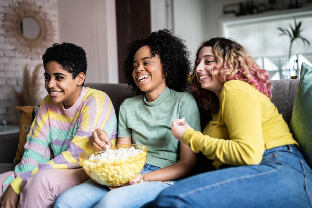 amici che guardano la tv e mangiano popcorn a casa - alternative health care foto e immagini stock