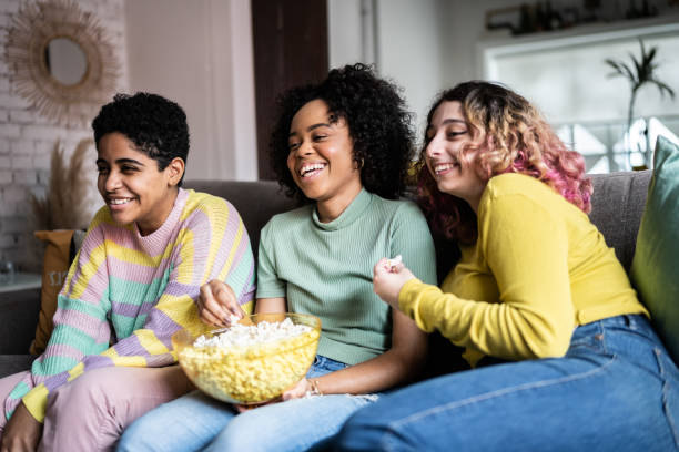 Friends watching TV and eating popcorn at home