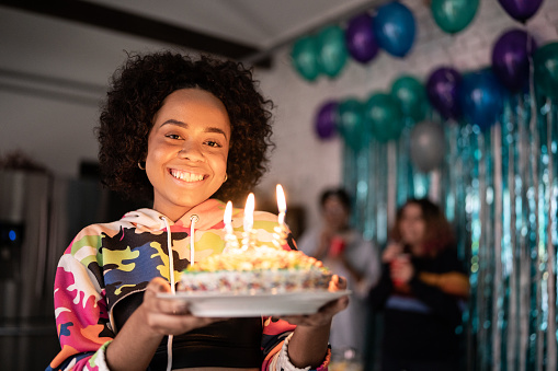 Portrait of a young woman holding a birthday cake at home