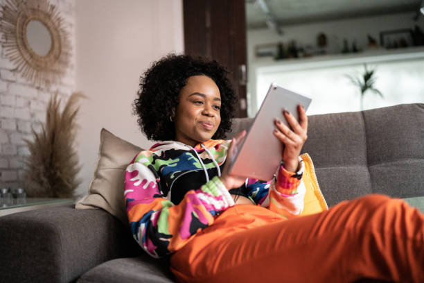 junge frau mit digitalem tablet zu hause - people reading stock-fotos und bilder