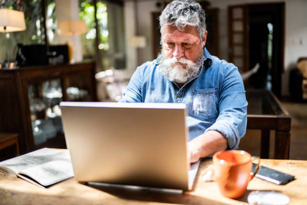 istock Senior man using a laptop at home 1345489314