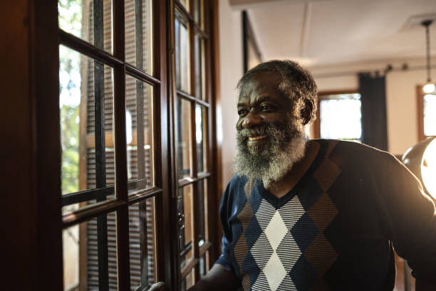 istock Senior man looking through the window at home 1345489494