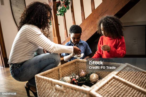Mother And Children Getting The Christmas Ornaments To Decorate The House Stock Photo - Download Image Now