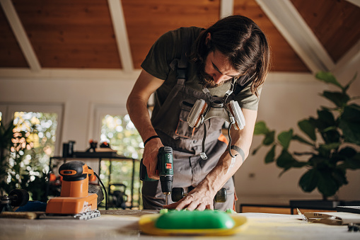 One man, young male wearing protective mask while repairing his skateboard at his repair shop at home.