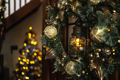 Christmas wreath on house door, sparking holiday spirit. Festive scene as wreath enhances door, reflecting Yuletide joy. Christmas wreath symbolizes warm, festive Christmas mood.