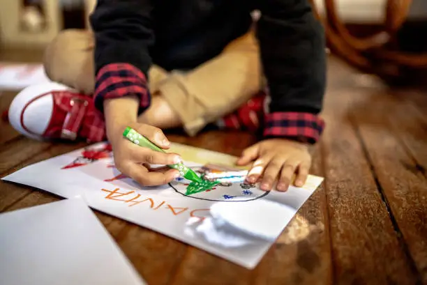 Photo of Boy drawing on Christmas card at home