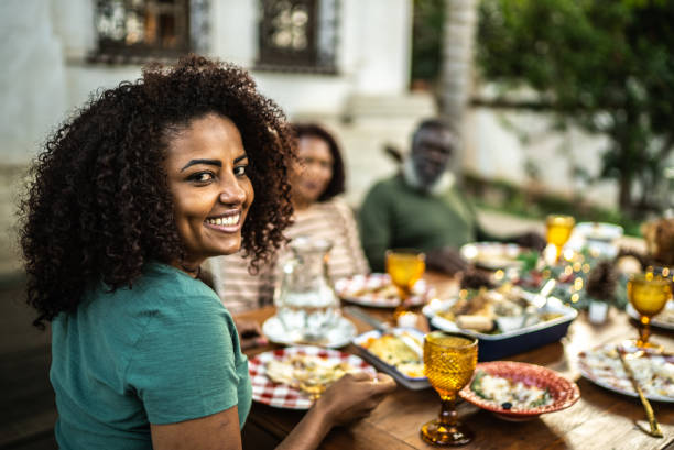 Portrait of a mid adult woman eating with family on Christmas at home Portrait of a mid adult woman eating with family on Christmas at home black people eating stock pictures, royalty-free photos & images