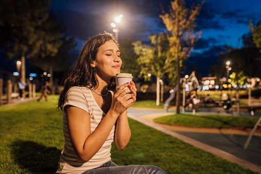 Portrait of a beautiful girl enjoying outdoors in the evening and enjoying coffee.
