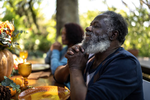 istock Senior man saying grace before Thanksgiving lunch at home 1345496497