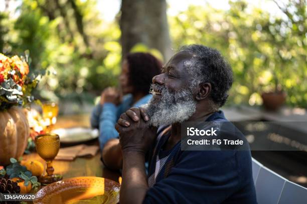 Senior Man Saying Grace Before Thanksgiving Lunch At Home Stock Photo - Download Image Now