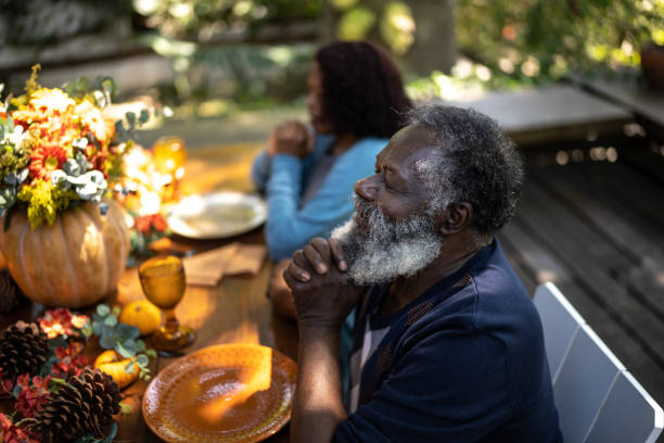 istock Senior man saying grace before Thanksgiving lunch at home 1345496623