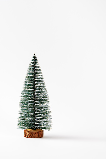 Beautiful fake miniature Christmas tree not decorated over a white background. Small Christmas tree. Copy space, front view. Isolated